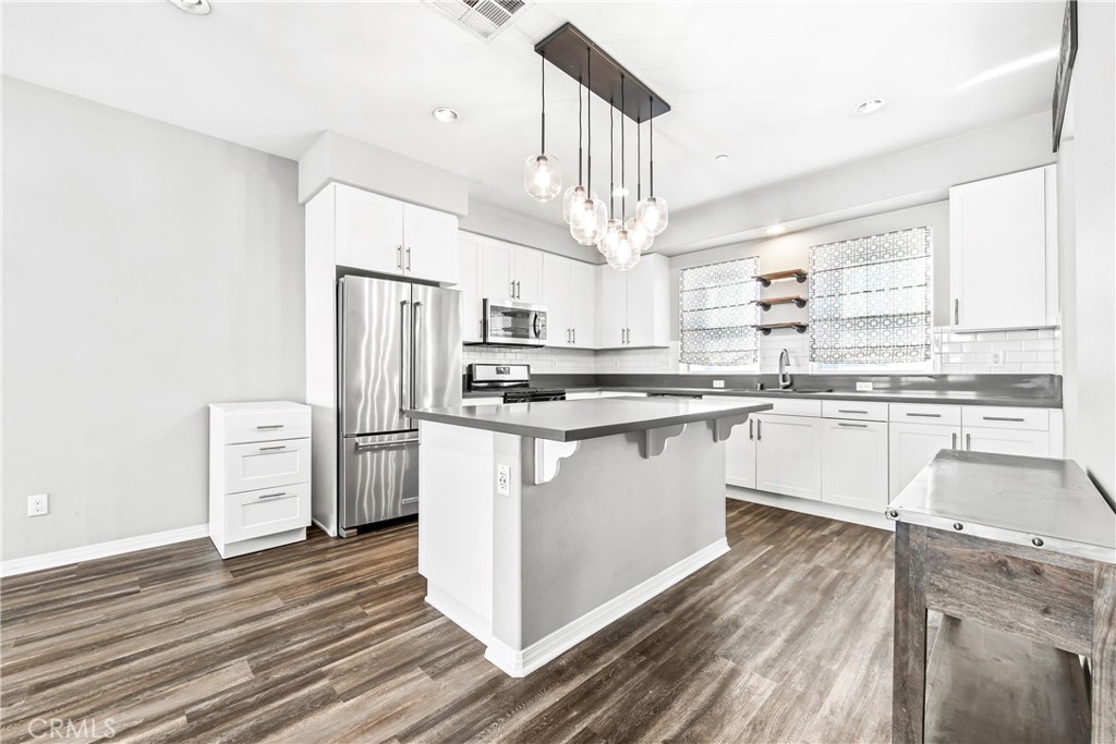 6331 Pacific Way Westminster, CA 92683 - Photo 3 of 38 a kitchen with stainless steel appliances a refrigerator a sink dishwasher a stove and white cabinets with wooden floor
