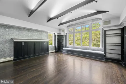 an empty room with wooden floor fireplace and windows