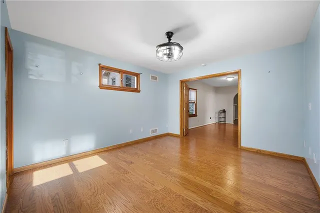 an empty room with wooden floor chandelier and windows