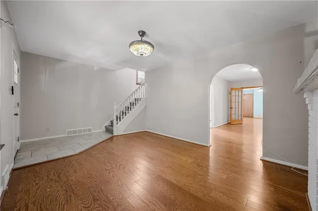 a view of an empty room with wooden floor and a chandelier