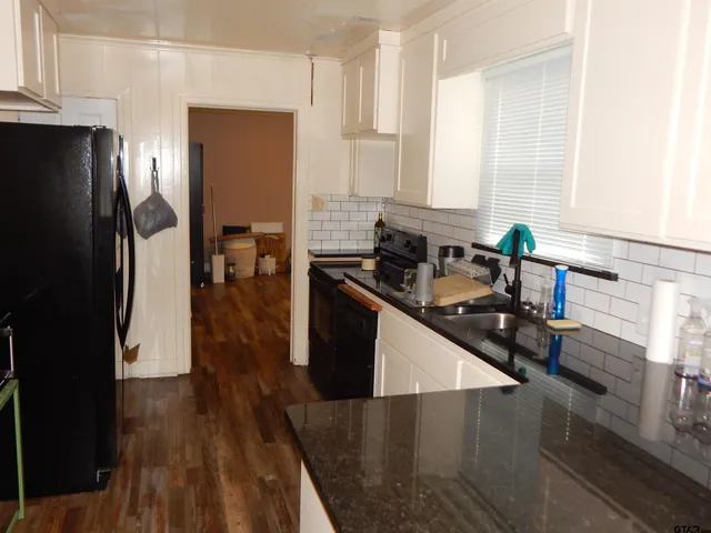 a kitchen with stainless steel appliances a sink a stove a refrigerator and wooden floor