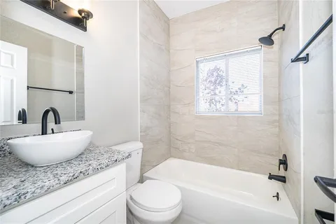 a bathroom with a granite countertop sink a mirror a bathtub and a toilet