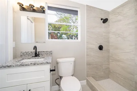 a bathroom with a granite countertop toilet a sink and a mirror