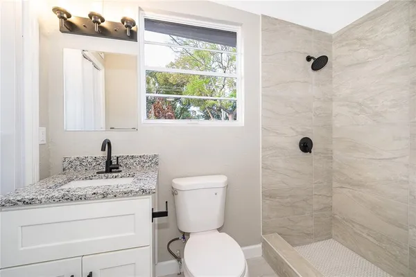 a bathroom with a granite countertop toilet a sink and a mirror