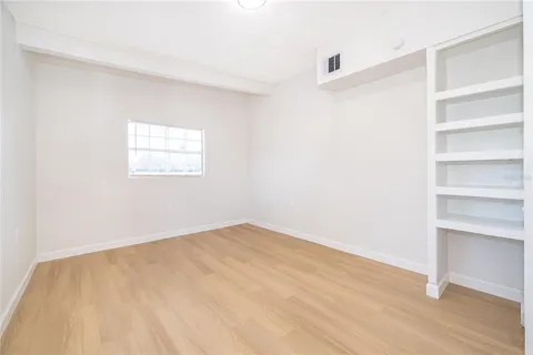 a view of an empty room with a window and wooden floor