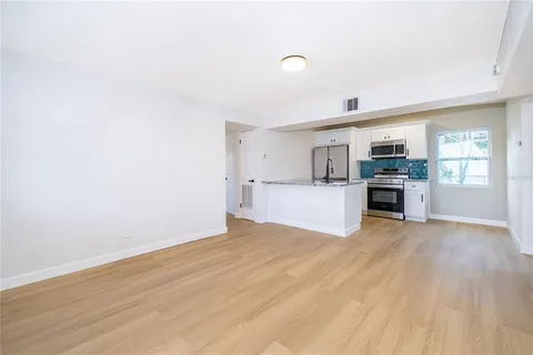 a view of a kitchen with wooden floor and electronic appliances