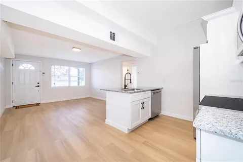 a view of a kitchen with granite countertop a sink and dishwasher with wooden floor