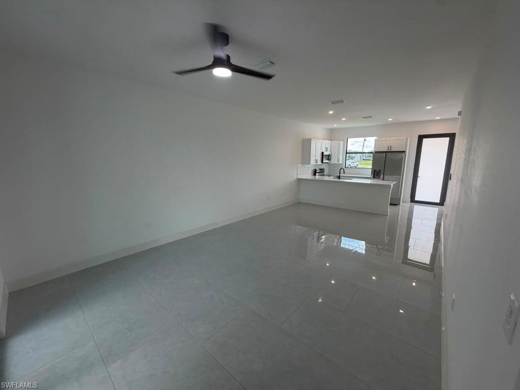 907 Homestead Road South Lehigh Acres, FL 33974 - Photo 32 of 43 Spacious open-concept living area featuring large format tile flooring and a modern ceiling fan