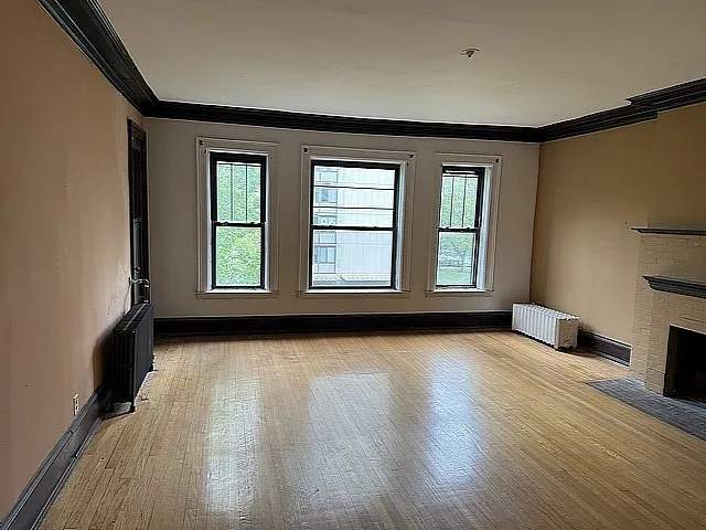 a view of an empty room with a window and wooden floor