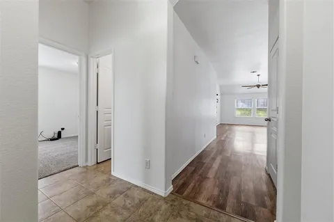 a view of a hallway with wooden floor and a bathroom