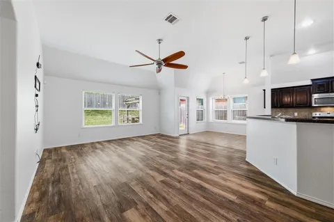 a view of a room with wooden floor and a ceiling fan