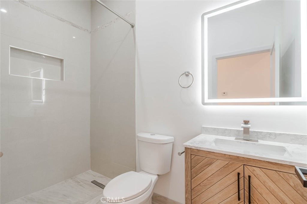 6852 1/2 Ranchito Avenue Van Nuys, CA 91405 - Photo 9 of 17 a bathroom with a toilet a sink a mirror and vanity