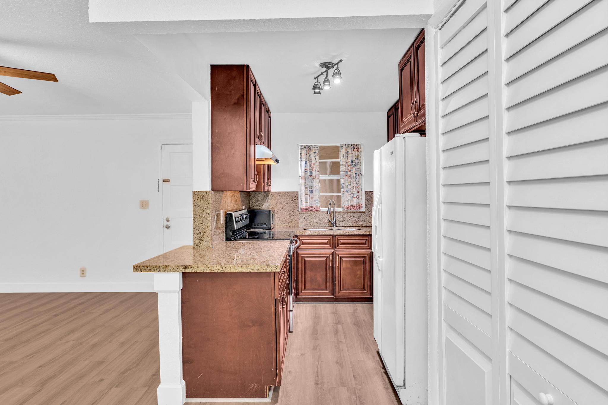 1291 Northwest 13th Street, Unit 445D Boca Raton, FL 33486 - Photo 21 of 50 a kitchen with stainless steel appliances granite countertop a sink a stove and a wooden floor