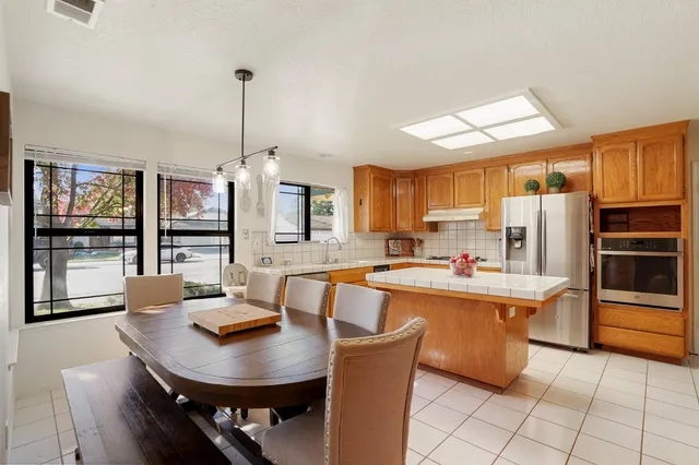 a kitchen with stainless steel appliances a dining table chairs and granite counter tops