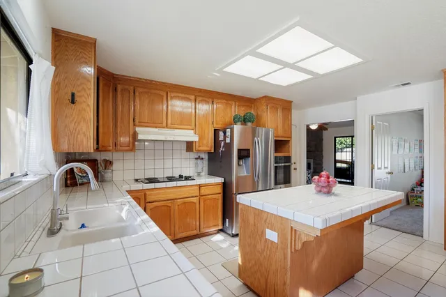 a kitchen with stainless steel appliances granite countertop a refrigerator a sink and a stove