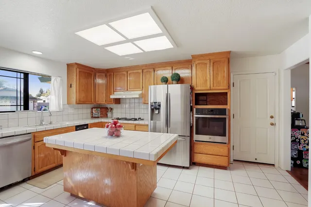 a kitchen with stainless steel appliances granite countertop a sink refrigerator and cabinets