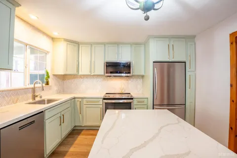 a kitchen with a sink a counter top space stainless steel appliances and cabinets