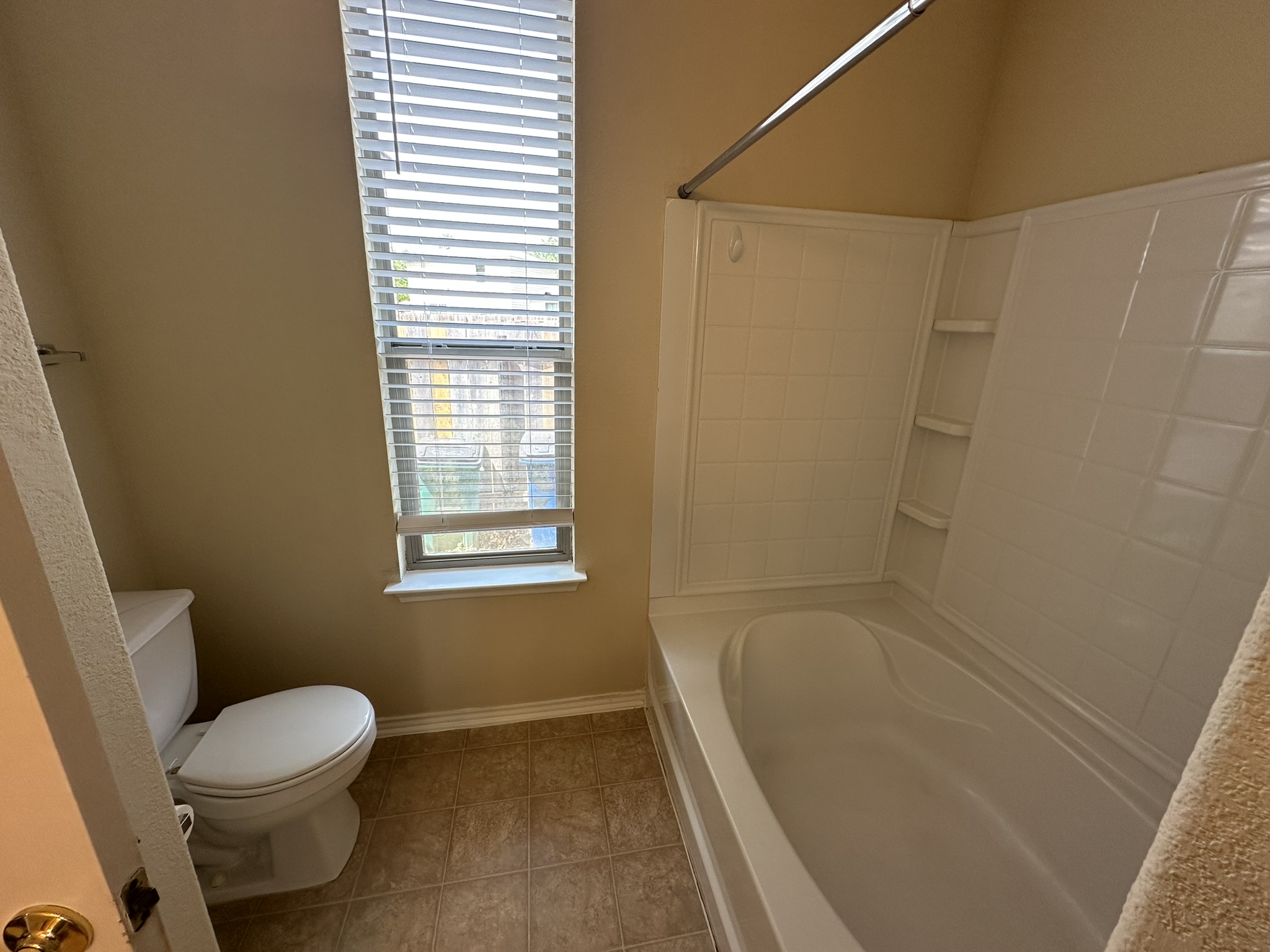 4507 Peach Grove Road Austin, TX 78744 - Photo 19 of 35 Natural light from a tall window illuminates a clean bathroom featuring a soaking tub.