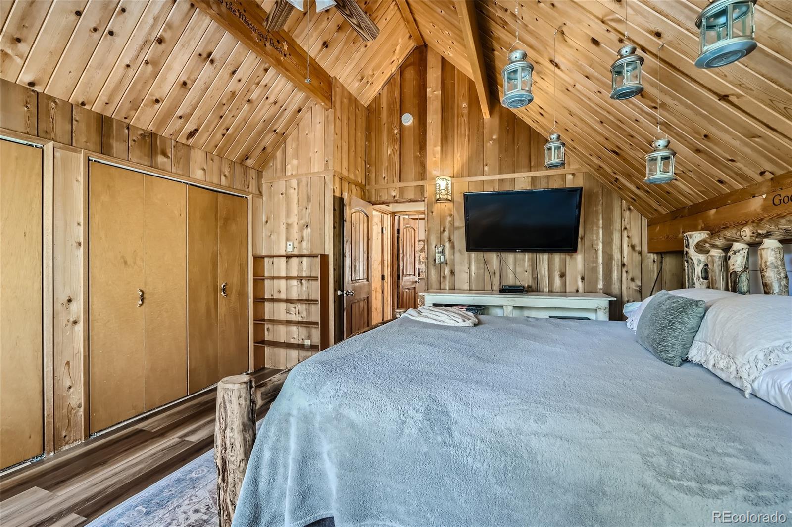 938 Valley Road Evergreen, CO 80439 - Photo 14 of 24 a bedroom with a bed a flat screen tv and a chandelier