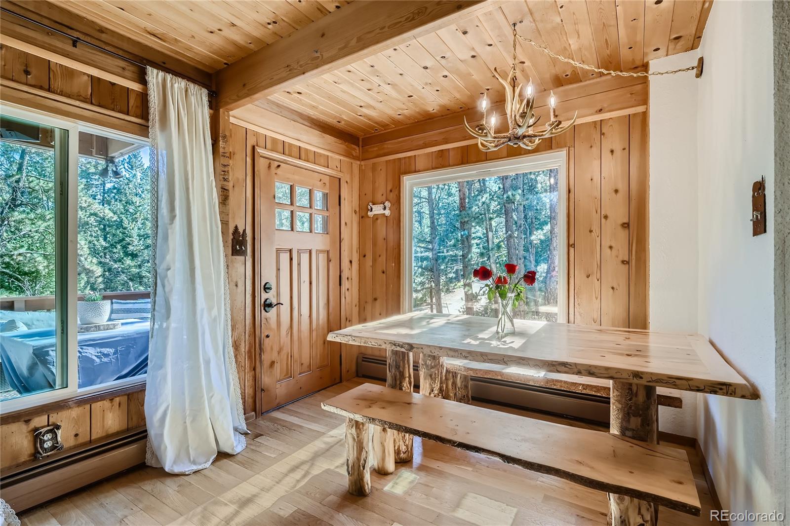 938 Valley Road Evergreen, CO 80439 - Photo 5 of 24 a dining room with wooden floor and a chandelier