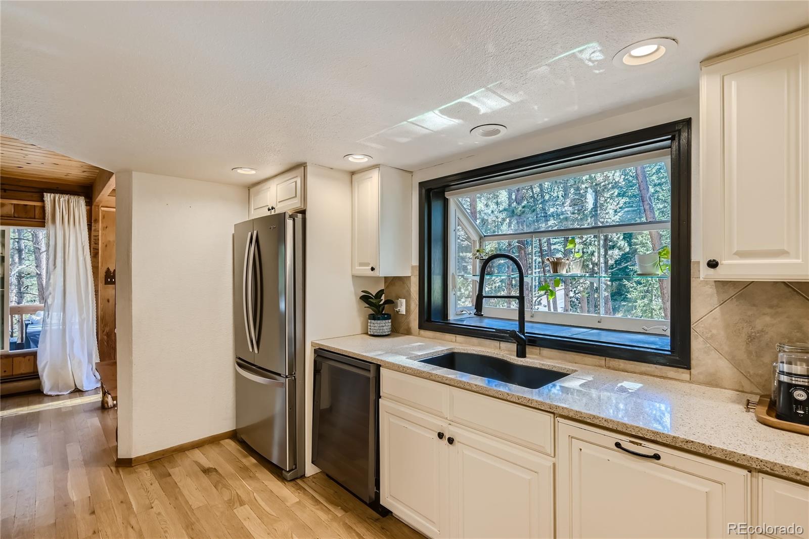 938 Valley Road Evergreen, CO 80439 - Photo 10 of 24 a kitchen with stainless steel appliances granite countertop a sink window and a refrigerator