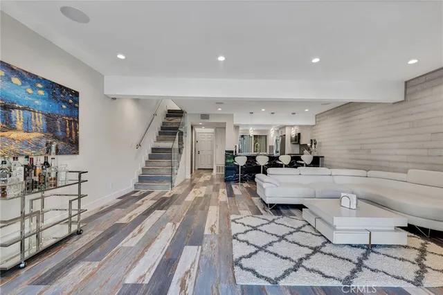 a living room with couches and kitchen view with wooden floor