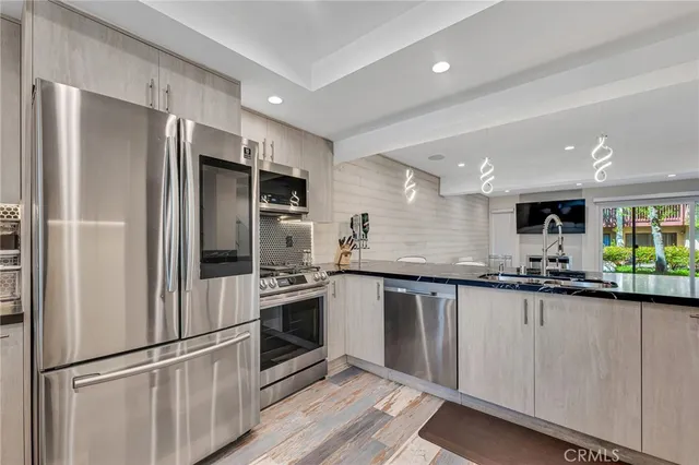 a modern kitchen with stainless steel appliances granite countertop a refrigerator and a sink