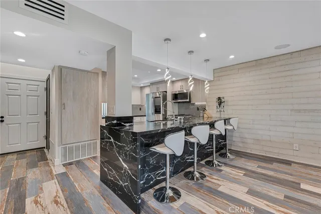 a kitchen with stainless steel appliances kitchen island granite countertop a table chairs sink and cabinets