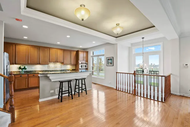 a kitchen with a table chairs wooden floors and a view of living room