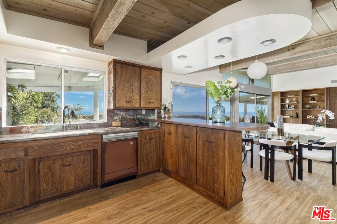 1126 Tellem Drive Pacific Palisades, CA 90272 - Photo 20 of 46 a kitchen with stainless steel appliances granite countertop wooden cabinets a dining table and chairs