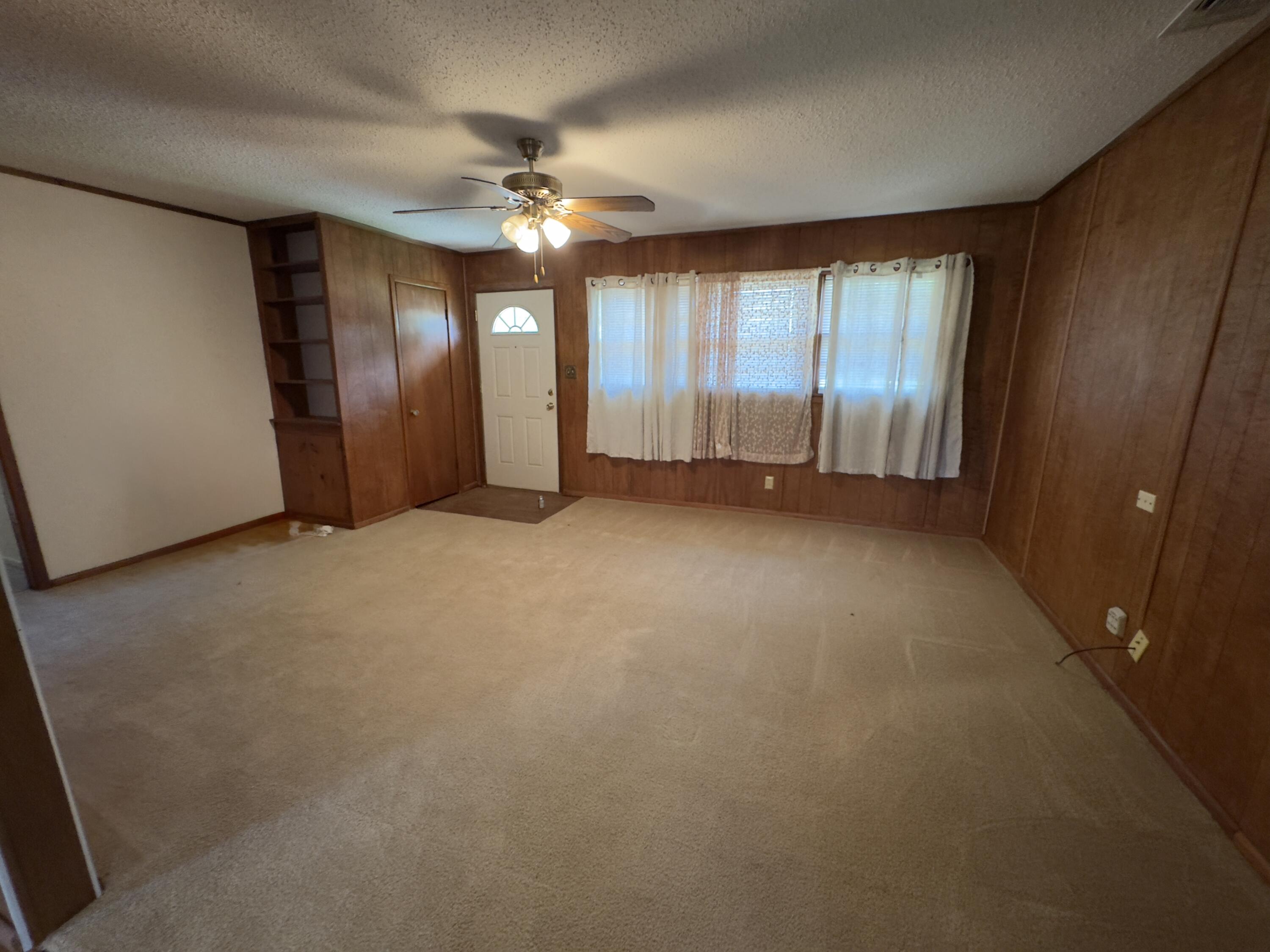 955 South 20th Street Slaton, TX 79364 - Photo 4 of 14 an empty room with chandelier fan and windows