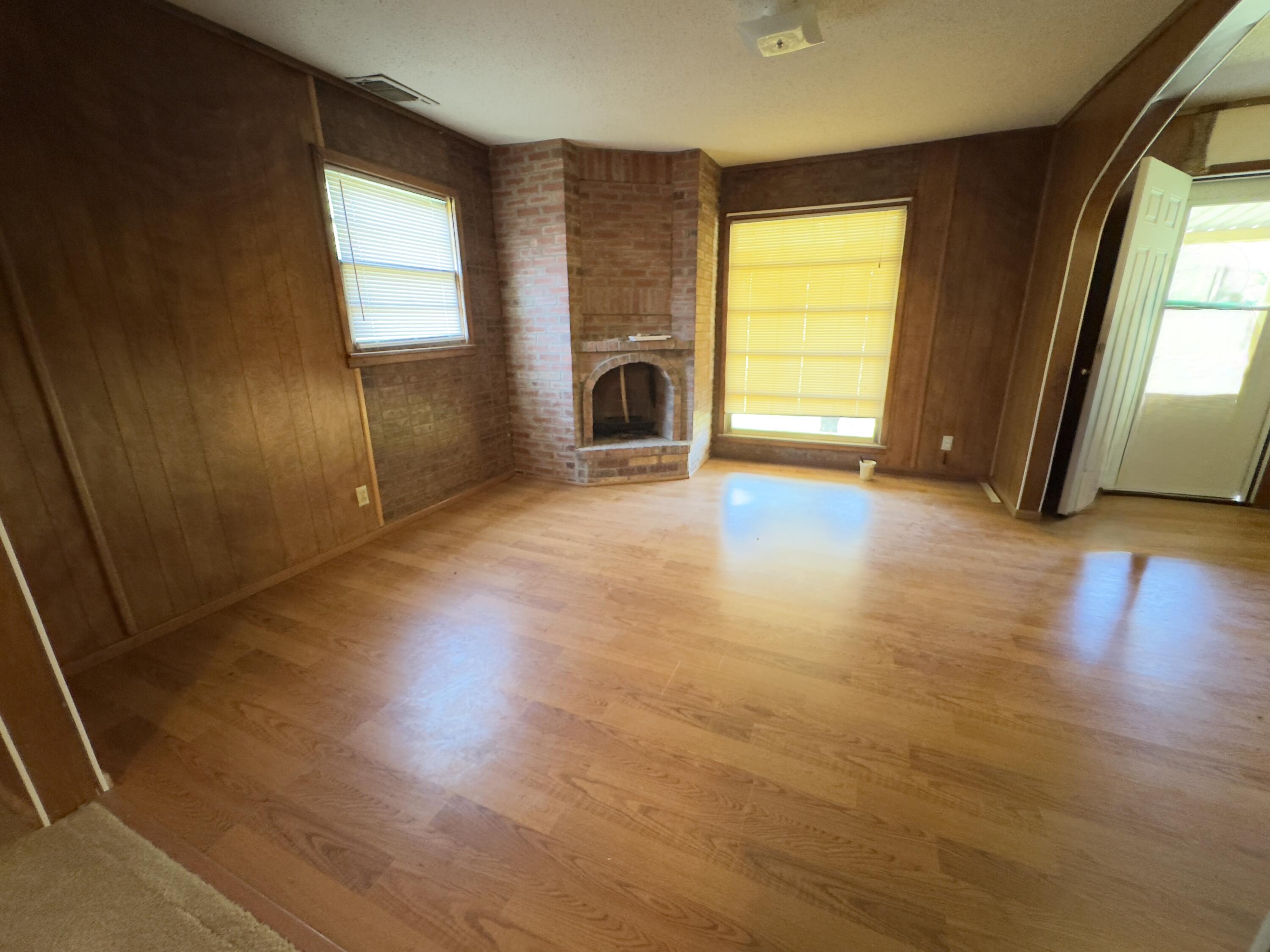 955 South 20th Street Slaton, TX 79364 - Photo 6 of 14 an empty room with wooden floor and windows