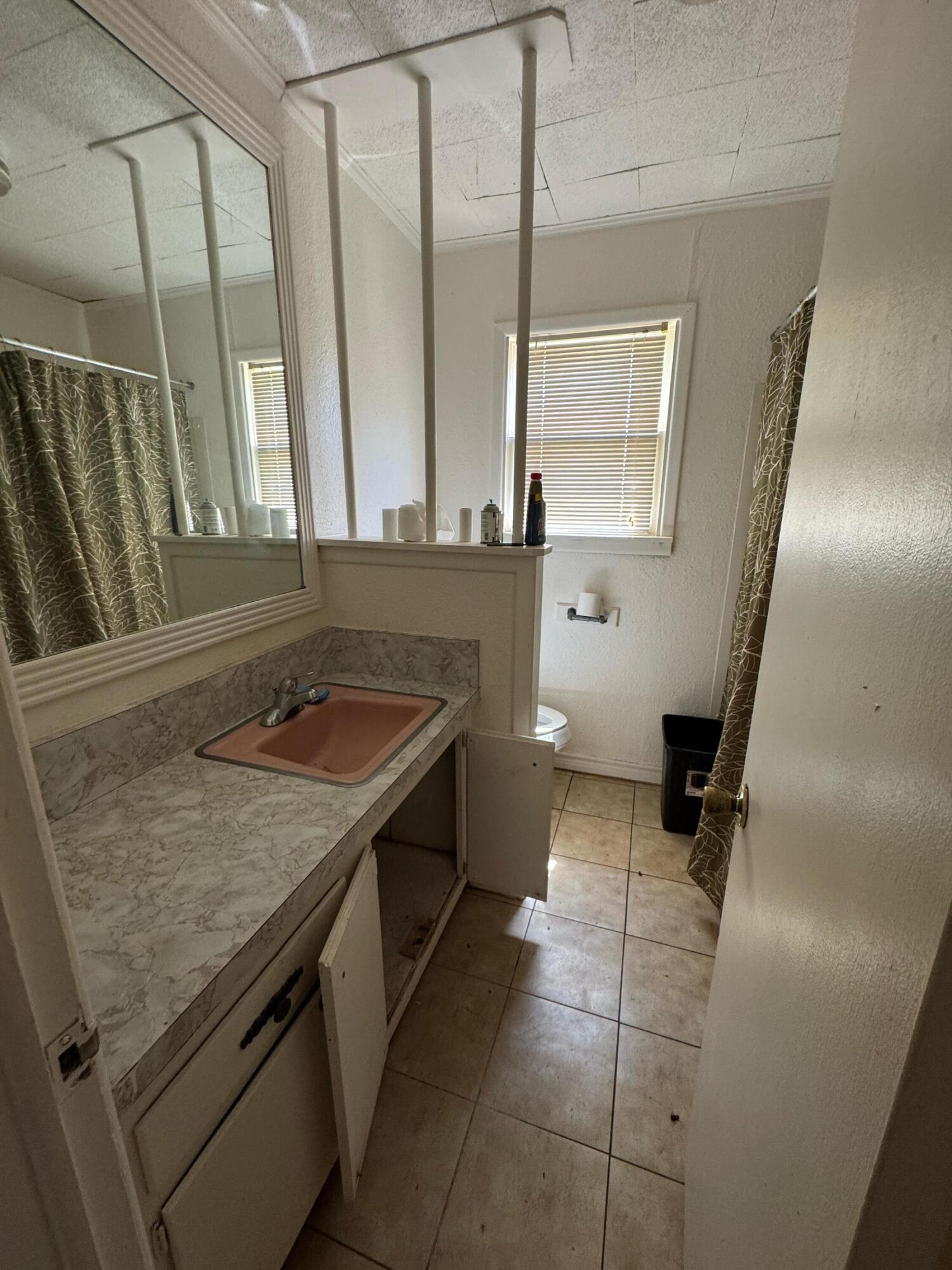 955 South 20th Street Slaton, TX 79364 - Photo 9 of 14 a bathroom with a sink a toilet and a mirror