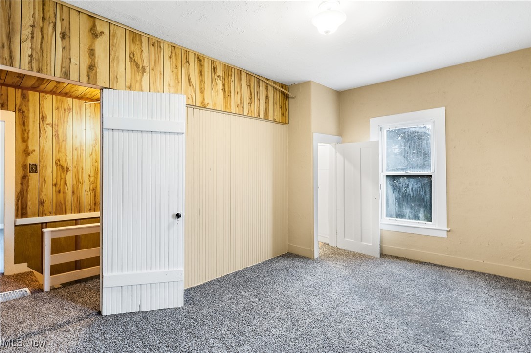7529 State Line Burghill, OH 44404 - Photo 15 of 23 Unfurnished bedroom featuring wooden walls, carpet, and a closet