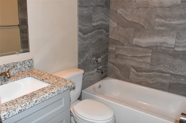 a bathroom with a granite countertop sink toilet and bathtub