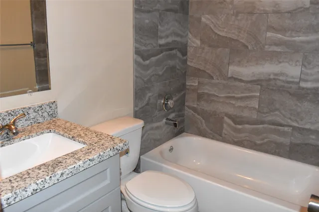 a bathroom with a granite countertop sink toilet and bathtub