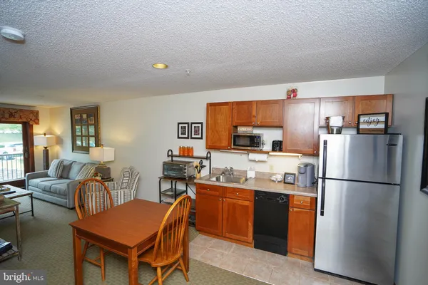 a kitchen with stainless steel appliances granite countertop a refrigerator a sink a stove a dining table and chairs