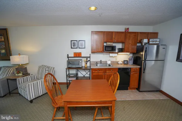 a living room with stainless steel appliances furniture a rug and a kitchen view