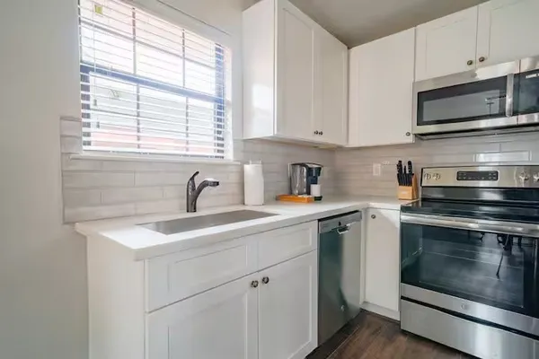 a kitchen with stainless steel appliances granite countertop white cabinets a sink and a stove