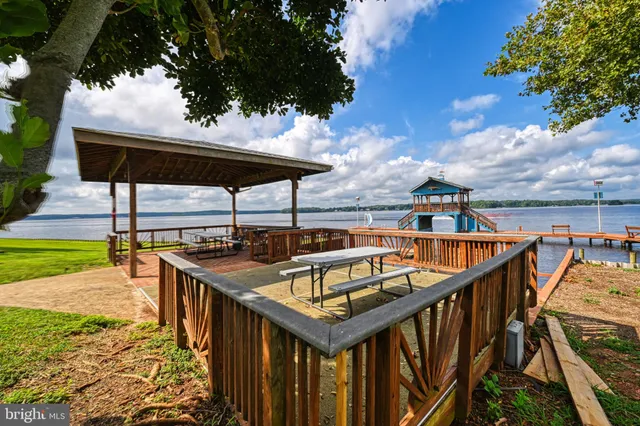 a view of a dining room and livingroom with furniture wooden floor a rug a painting and a chandelier