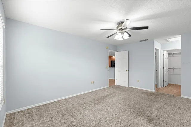 an empty room with closet and a ceiling fan