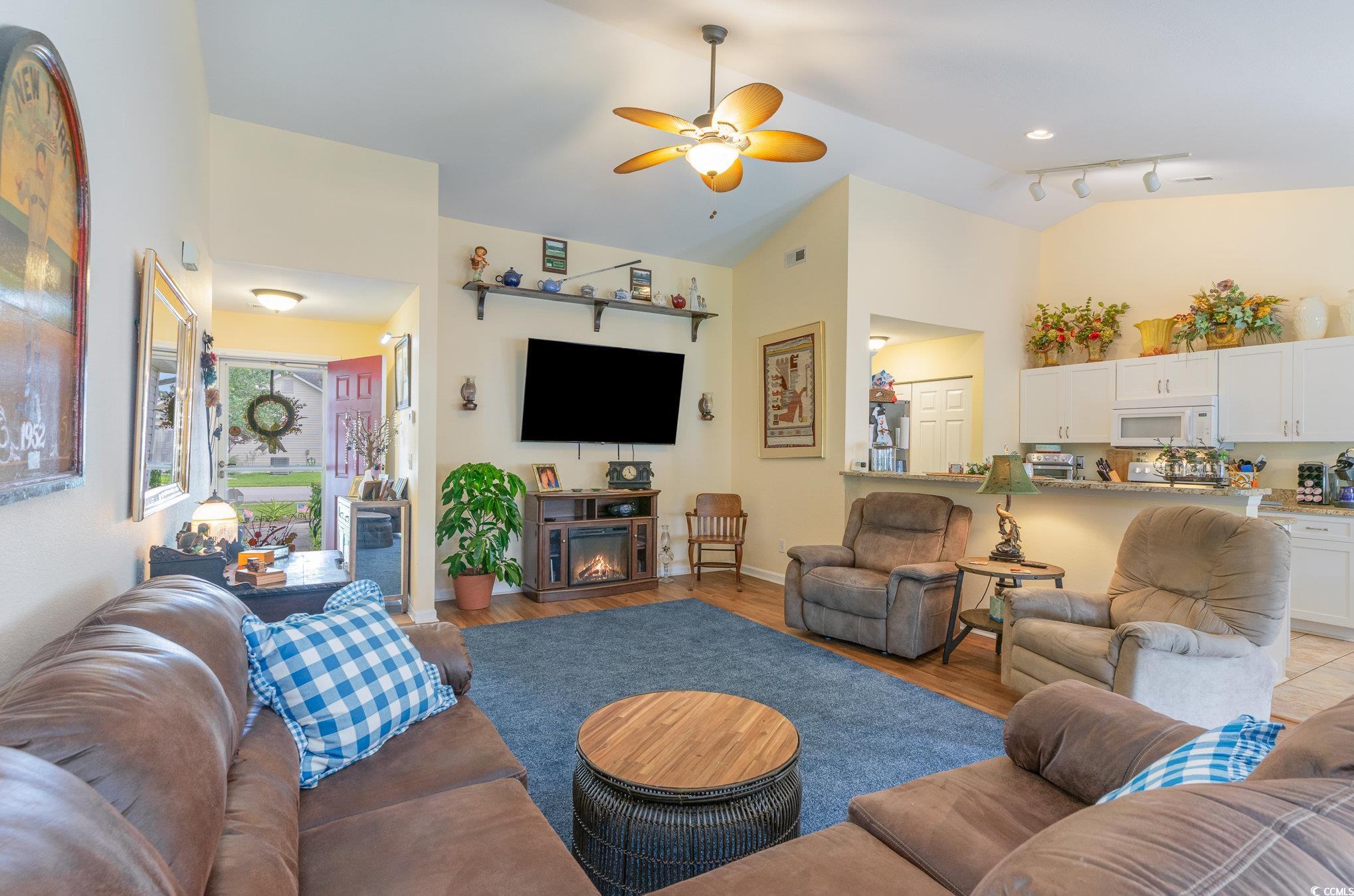 Living room featuring vaulted ceiling, rail lighti