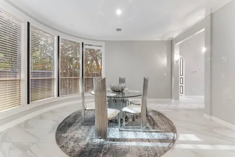 a dining room with wooden floor and a floor to ceiling window