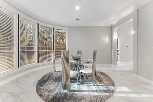a dining room with wooden floor and a floor to ceiling window