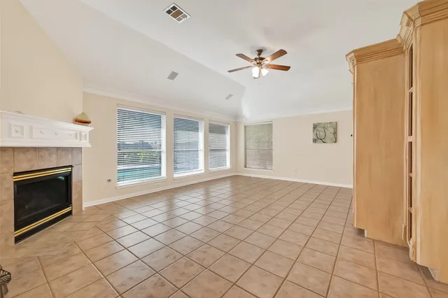 a view of an empty room with window and chandelier fan