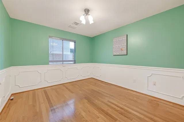 a view of an empty room with window and wooden floor