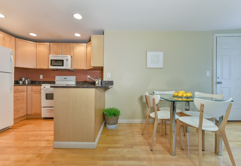 95 Second Street, Unit 3 Cambridge, MA 02141 - Photo 6 of 13 a kitchen with stainless steel appliances kitchen island granite countertop a table and chairs in it