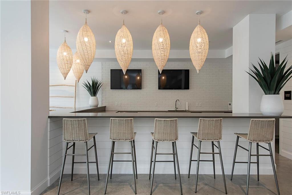 1111 Central Avenue, Unit 207 Naples, FL 34102 - Photo 17 of 18 a view of a kitchen with stainless steel appliances granite countertop a table and chairs in it