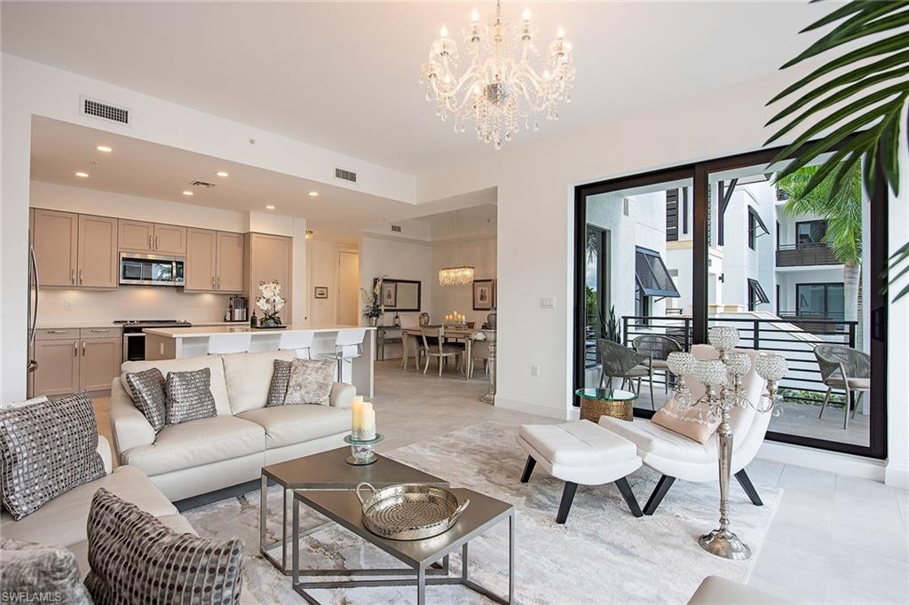 1111 Central Avenue, Unit 207 Naples, FL 34102 - Photo 4 of 18 a living room with furniture a chandelier and a dining table with kitchen view