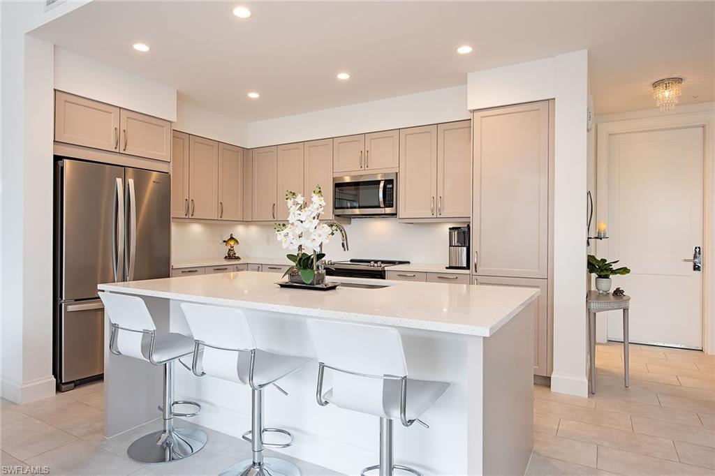 1111 Central Avenue, Unit 207 Naples, FL 34102 - Photo 6 of 18 a kitchen with kitchen island a refrigerator stove and microwave